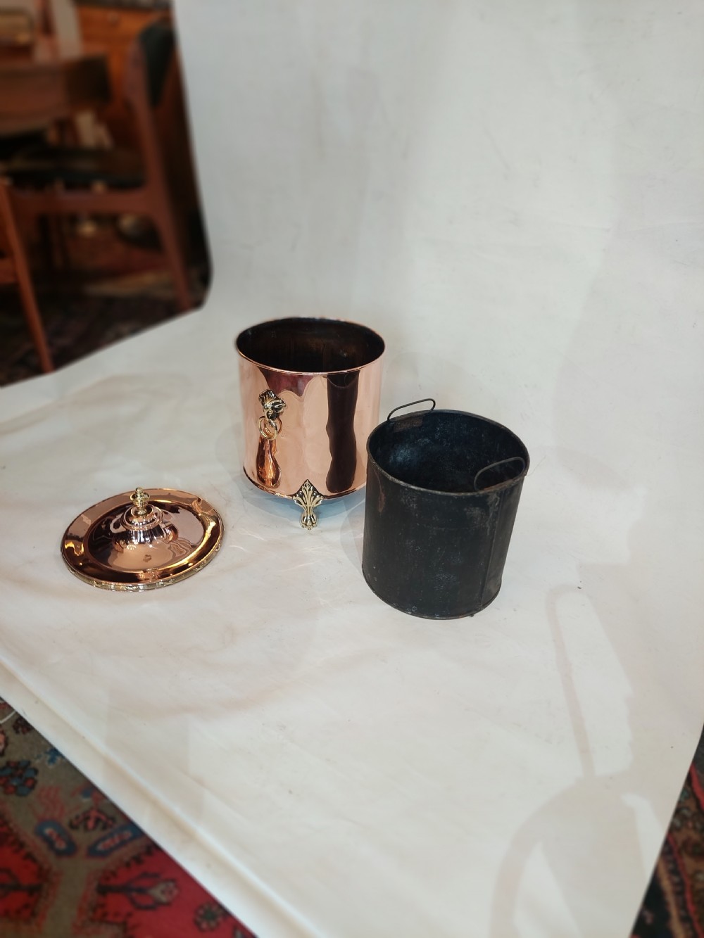 A cylindrical polished copper coal bucket featuring a fitted lid with a brass finial, side ring handles attached to lion mask mounts, and four detailed brass paw feet. View VII