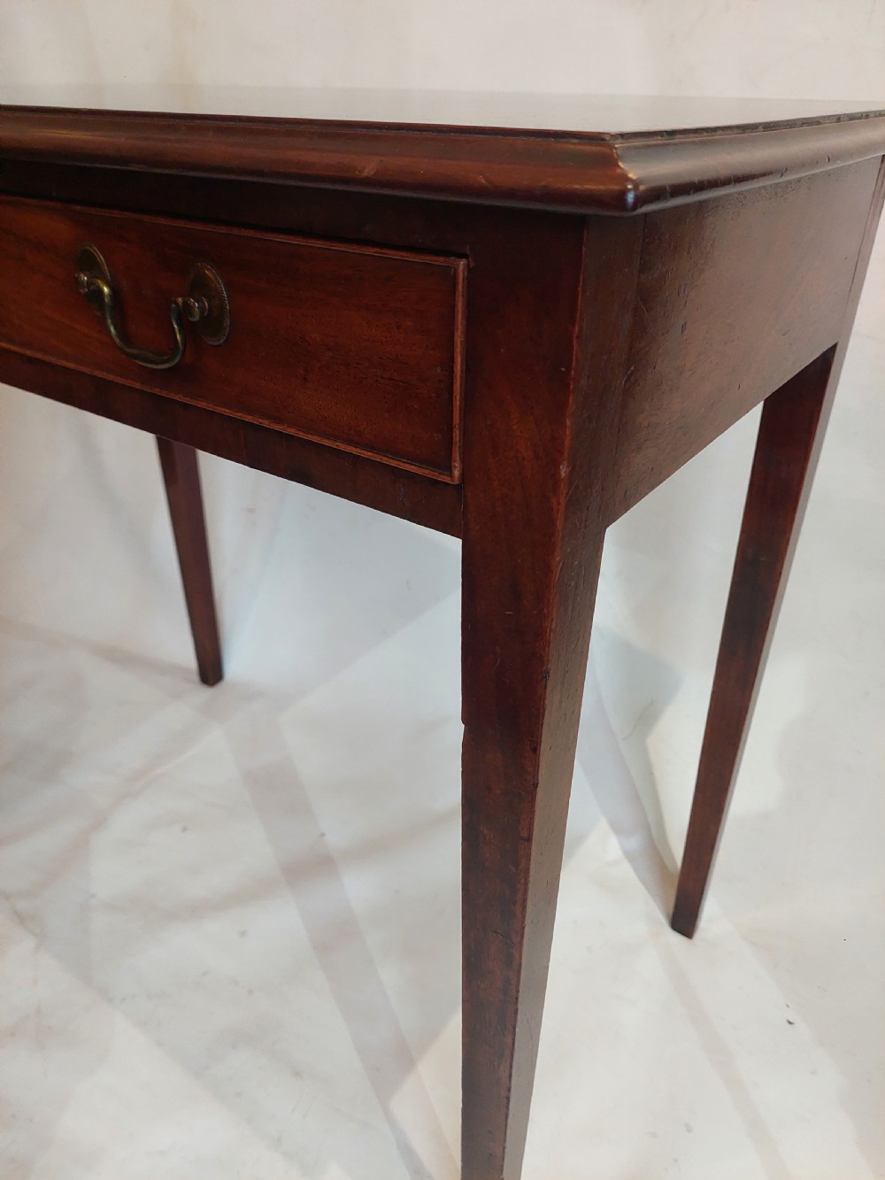 A mid-18th-century Georgian mahogany hall table featuring two drawer fronts with brass swan-neck handles and square tapered legs. View IV