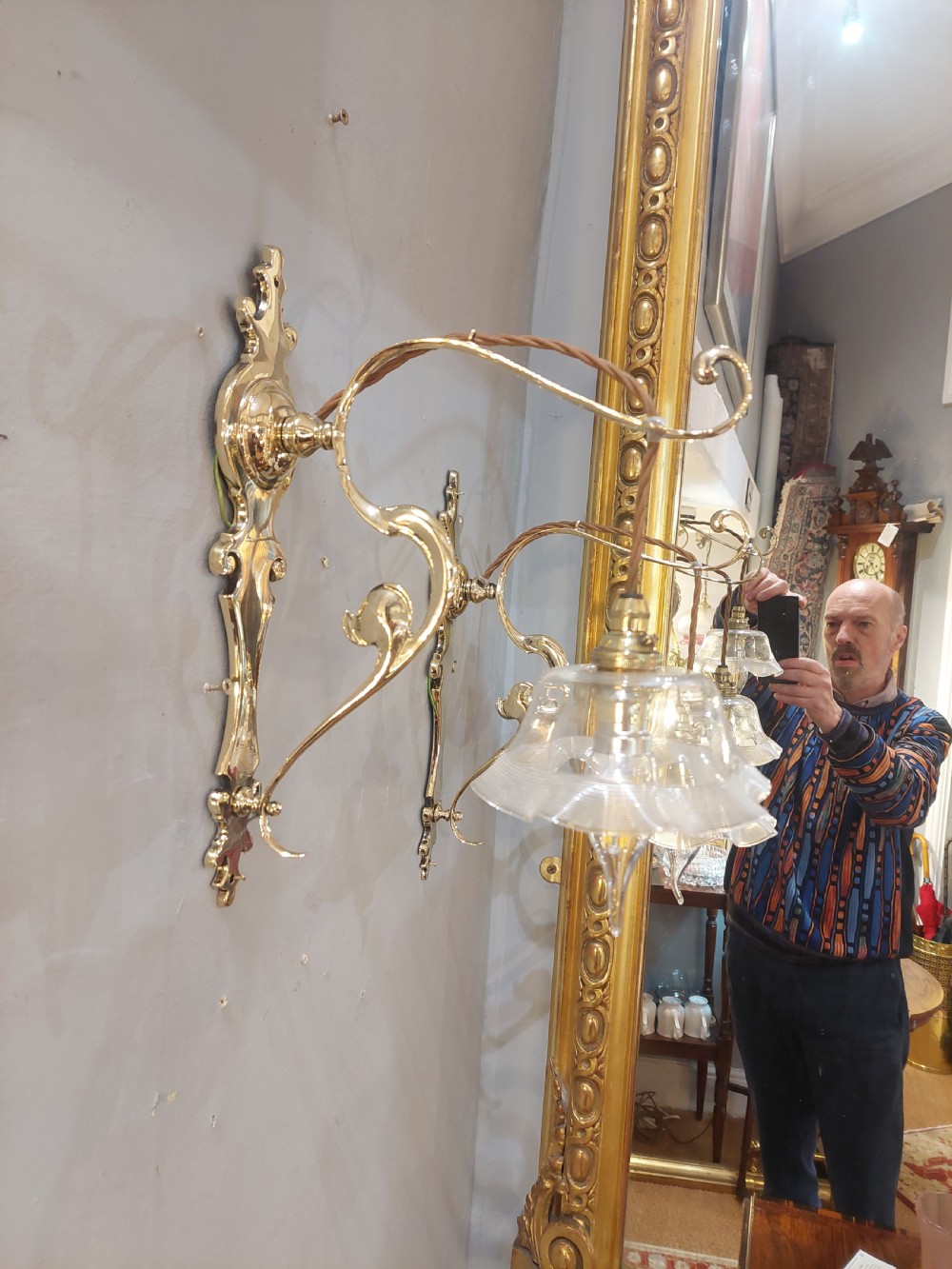 A pair of polished brass Art Nouveau wall sconces featuring decorative backplates, gooseneck arms, twisted flex, and ruffled clear glass shades. View VI