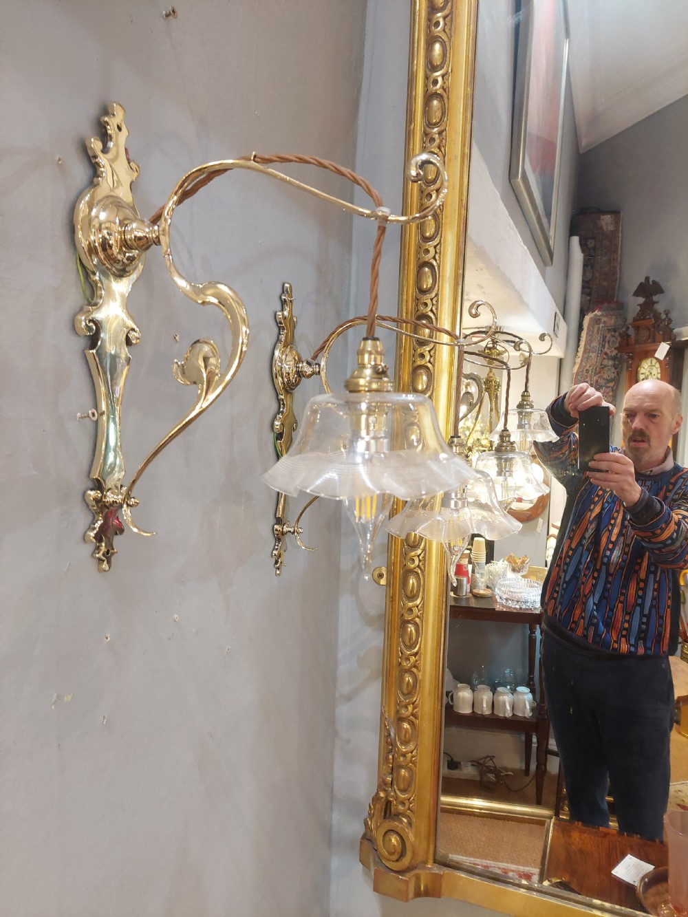 A pair of polished brass Art Nouveau wall sconces featuring decorative backplates, gooseneck arms, twisted flex, and ruffled clear glass shades. View VII