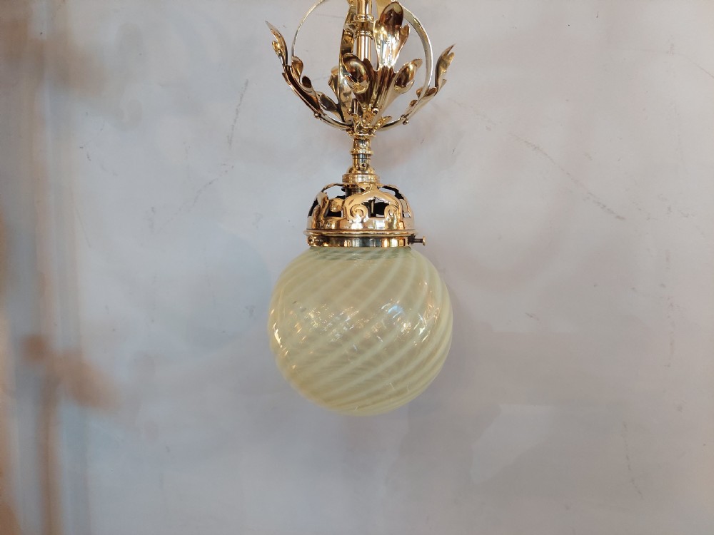 An Art Nouveau ceiling pendant light featuring polished brass scrollwork and leaf detailing suspending a swirled pale green glass globe shade. View II
