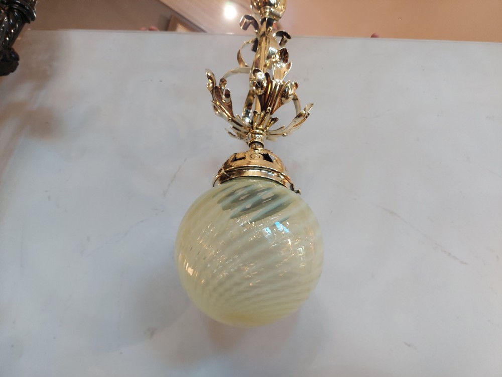 An Art Nouveau ceiling pendant light featuring polished brass scrollwork and leaf detailing suspending a swirled pale green glass globe shade. View VI