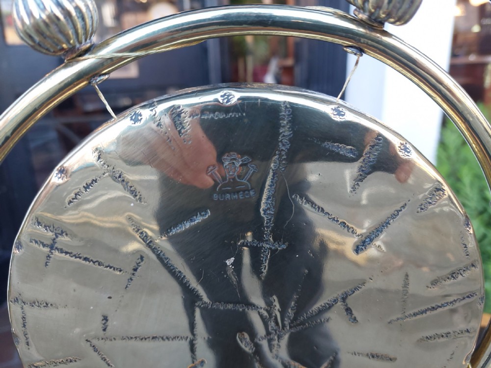 A late 19th-century polished metal tabletop gong with a circular hammered centre plate, ribbed decorative beads, a framed stand, and an attached hanging striker. View VI