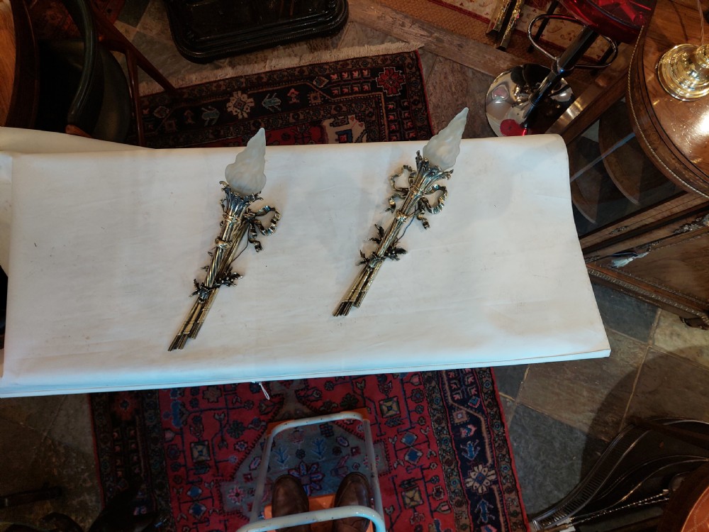 A pair of early twentieth-century Neoclassical brass wall sconces shaped as torches with ribbon bow details and frosted flame glass shades. View II