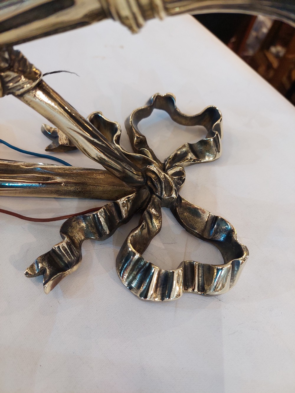 A pair of early twentieth-century Neoclassical brass wall sconces shaped as torches with ribbon bow details and frosted flame glass shades. View VI