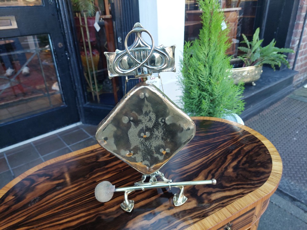 An Art Nouveau silver-plated table gong featuring a diamond-shaped suspended plate, stylized arched metal frame, and a mallet resting on a dual-pronged base. View II