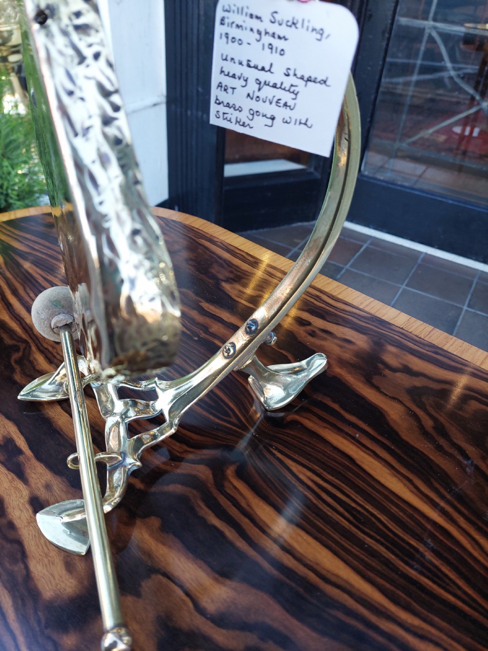 An Art Nouveau silver-plated table gong featuring a diamond-shaped suspended plate, stylized arched metal frame, and a mallet resting on a dual-pronged base. View IV