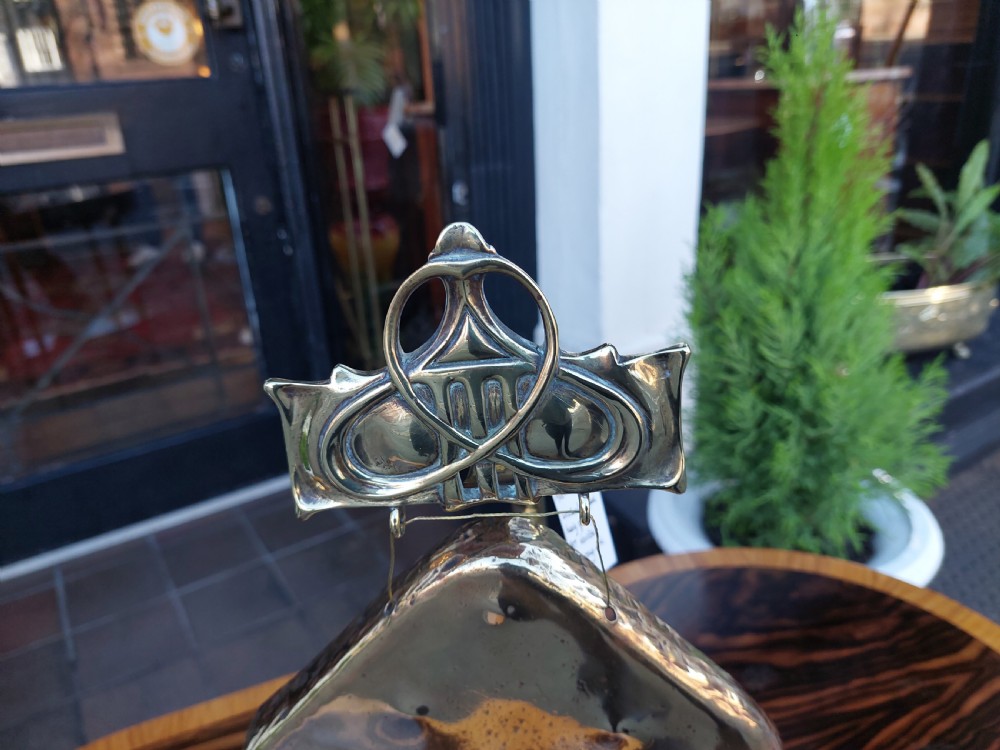 An Art Nouveau silver-plated table gong featuring a diamond-shaped suspended plate, stylized arched metal frame, and a mallet resting on a dual-pronged base. View VII
