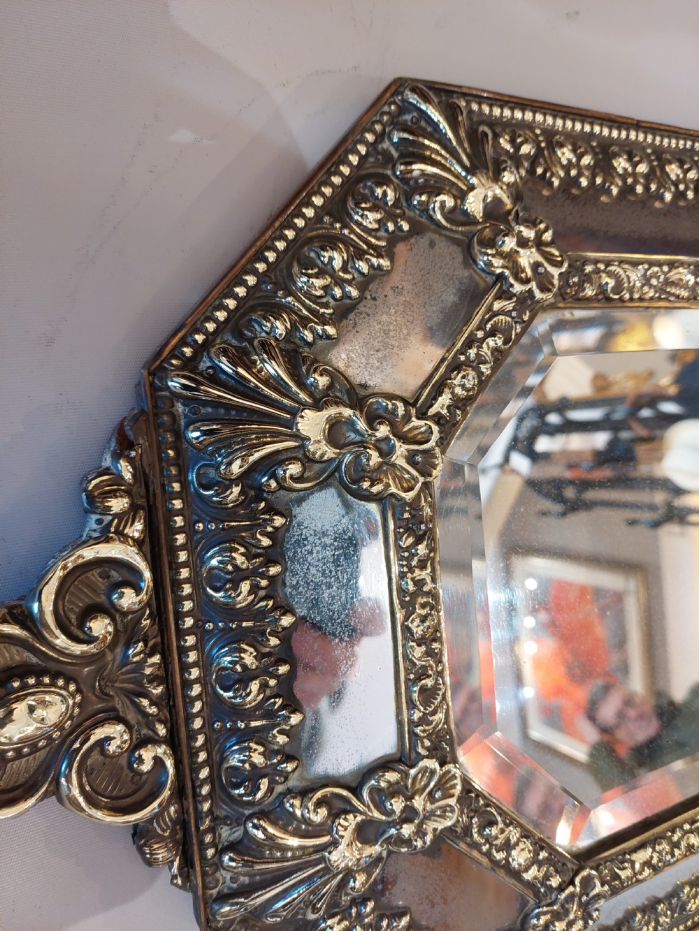An antique Victorian octagonal cushion mirror featuring an embossed brass frame with floral cresting and mirrored border sections. View II