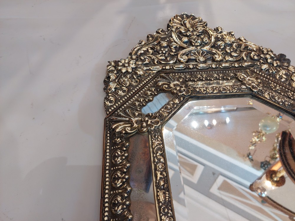 An antique Victorian octagonal cushion mirror featuring an embossed brass frame with floral cresting and mirrored border sections. View III
