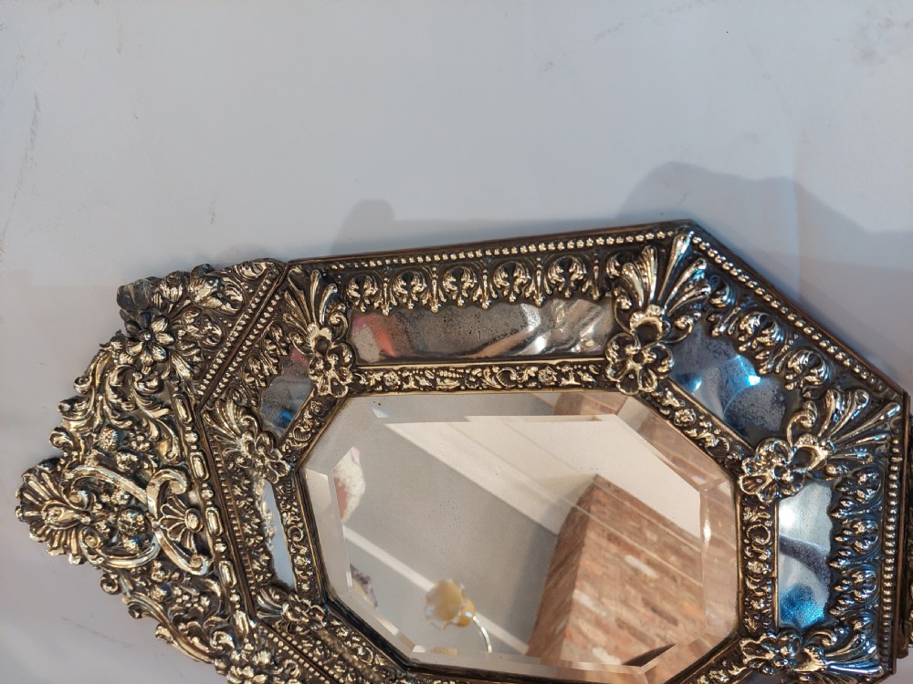 An antique Victorian octagonal cushion mirror featuring an embossed brass frame with floral cresting and mirrored border sections. View IV