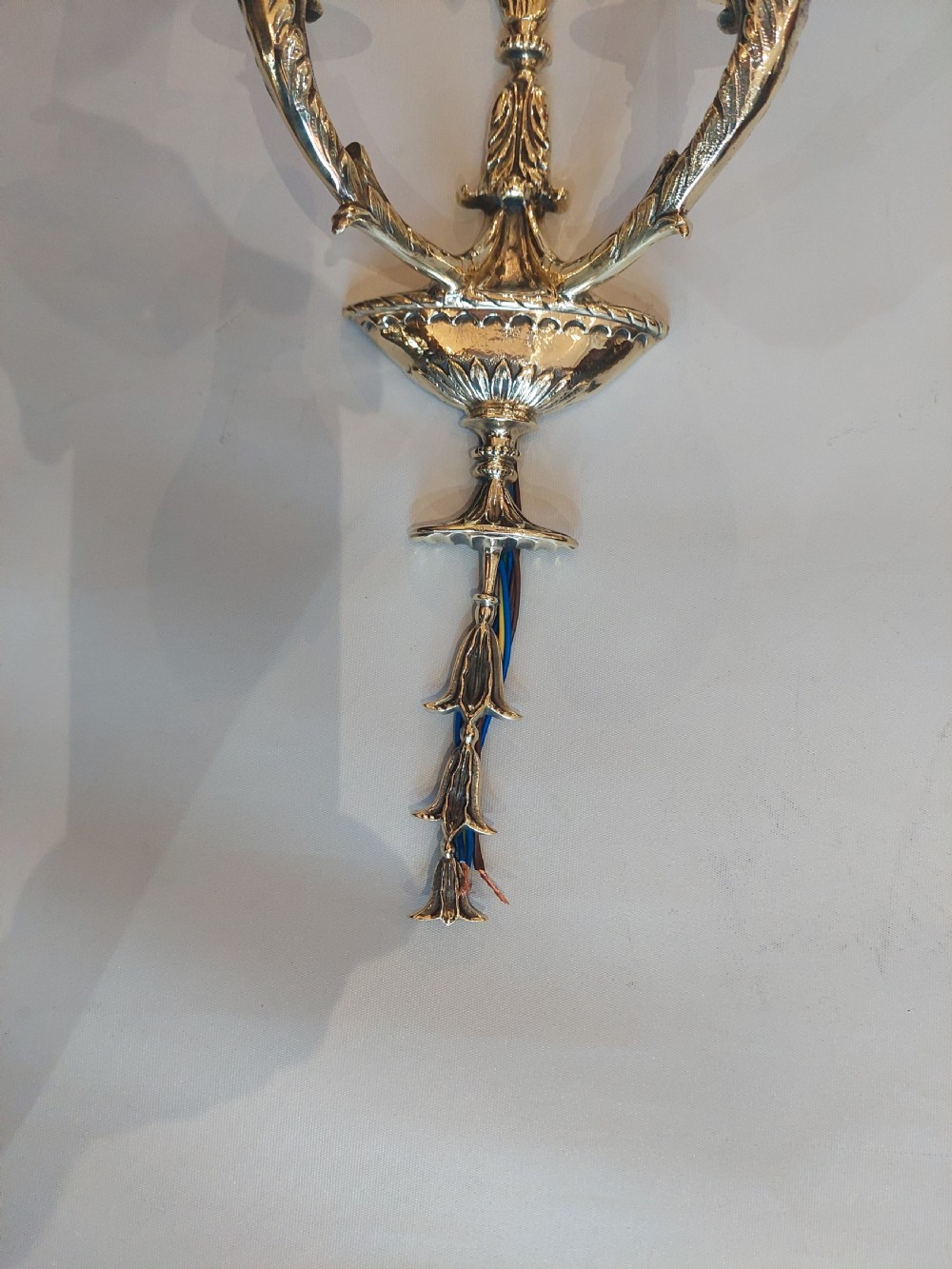 A set of four early 20th-century gilt brass twin-arm wall sconces featuring Neoclassical urn and anthemion motifs. View VII