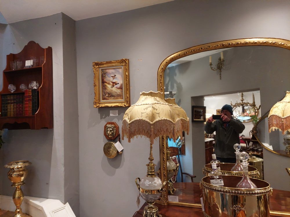 A set of four early 20th-century gilt brass twin-arm wall sconces featuring Neoclassical urn and anthemion motifs. View VIII