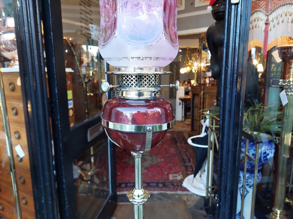 A late 19th-century brass and copper floor-standing oil lamp featuring claw feet and a cranberry glass font and shade. View VII