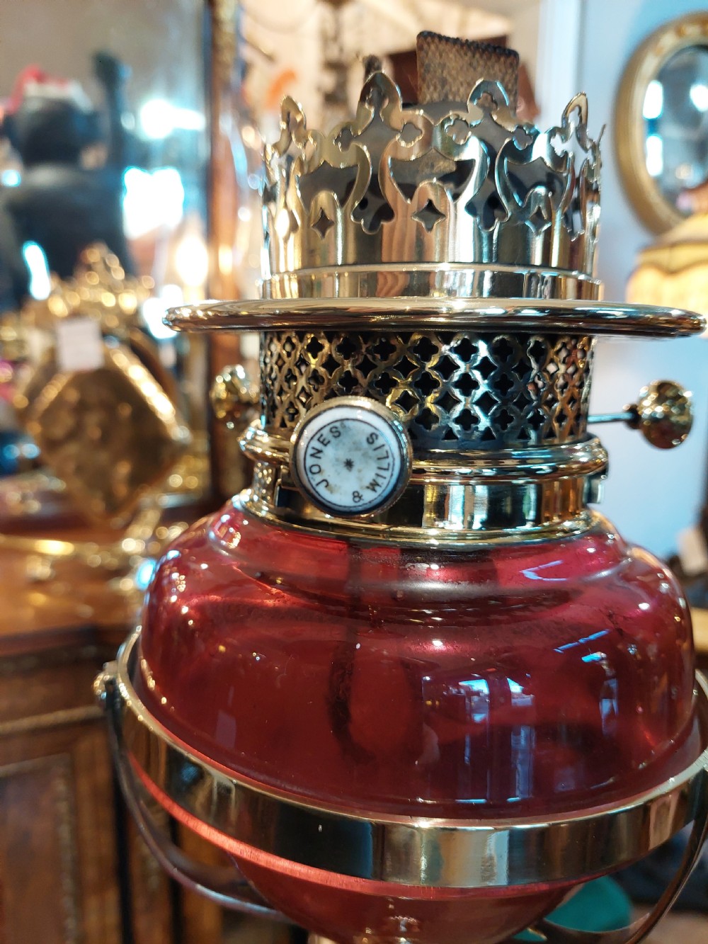 A late 19th-century brass and copper floor-standing oil lamp featuring claw feet and a cranberry glass font and shade. View X