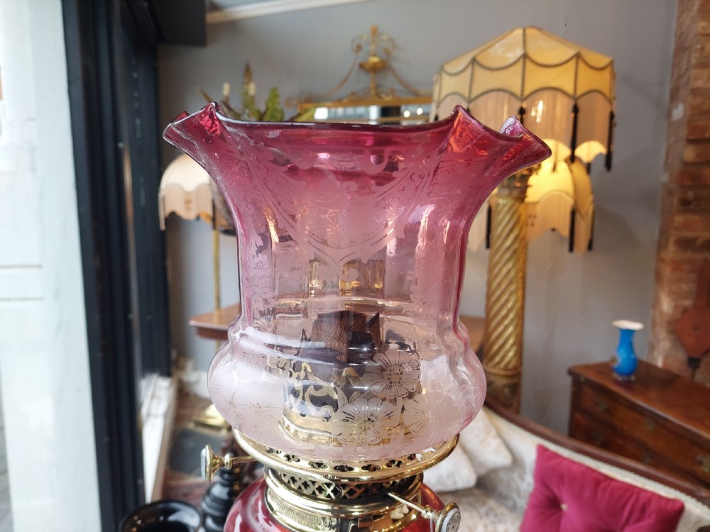 A late 19th-century brass and copper floor-standing oil lamp featuring claw feet and a cranberry glass font and shade. View XII