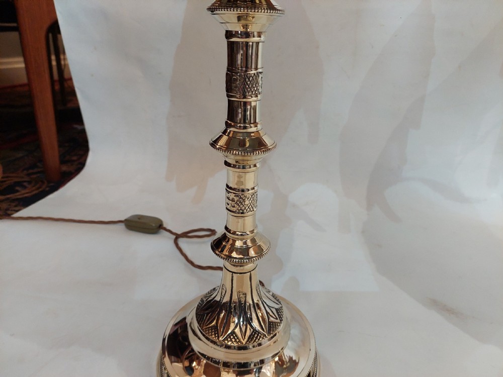 A pair of 19th-century Gothic Revival cast brass table lamps featuring knopped columns and dome-shaped green patterned fabric shades with long fringe and tassels. View IV