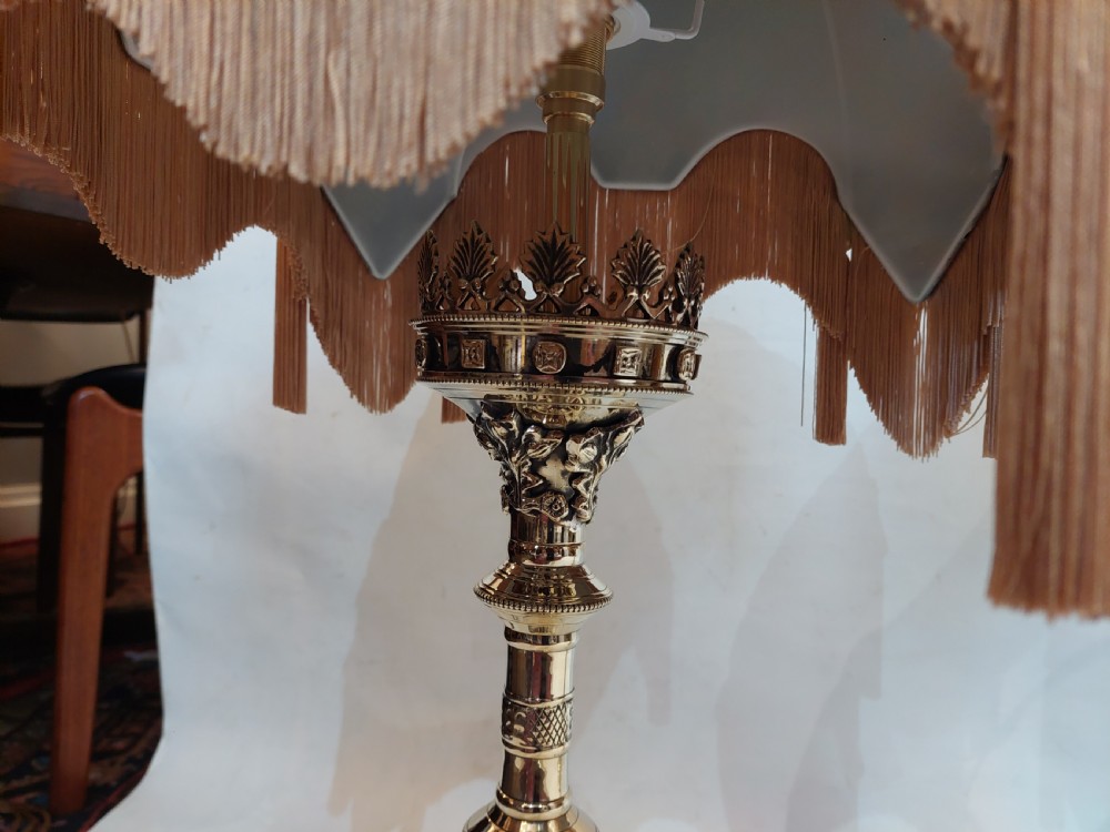 A pair of 19th-century Gothic Revival cast brass table lamps featuring knopped columns and dome-shaped green patterned fabric shades with long fringe and tassels. View V