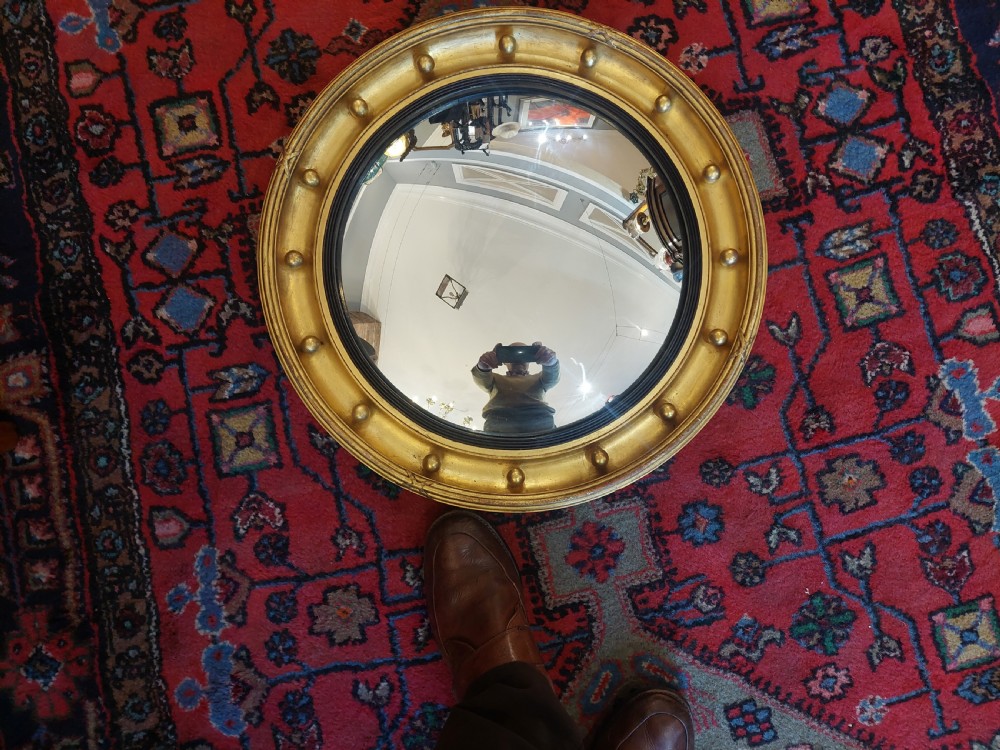 A 19th-century Regency style circular giltwood convex mirror decorated with spherules along the frame and an ebonised inner slip. View V