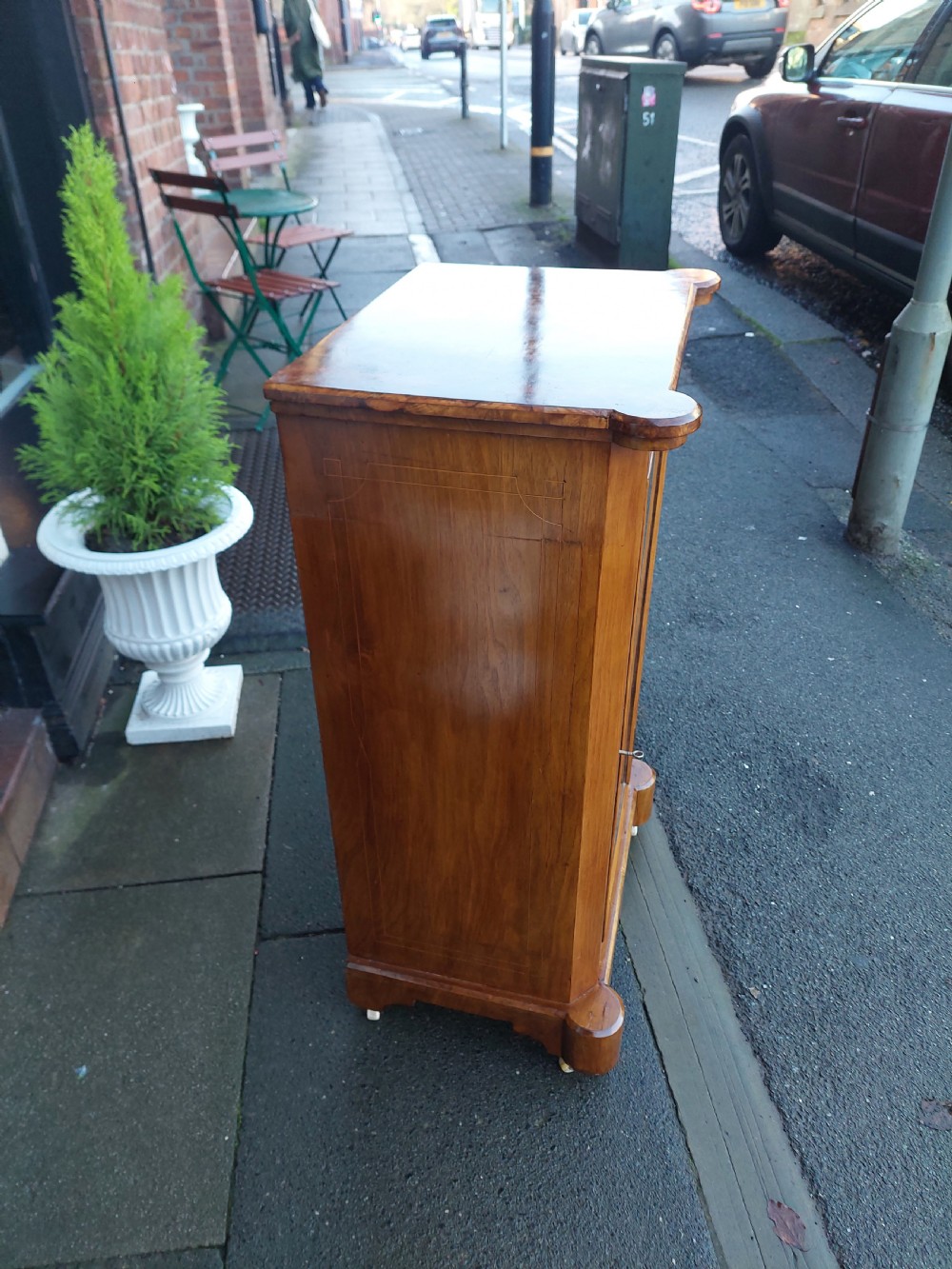 A Victorian walnut music cabinet with a glazed single door, floral marquetry inlay, three internal shelves, and a plinth base on castors. View III