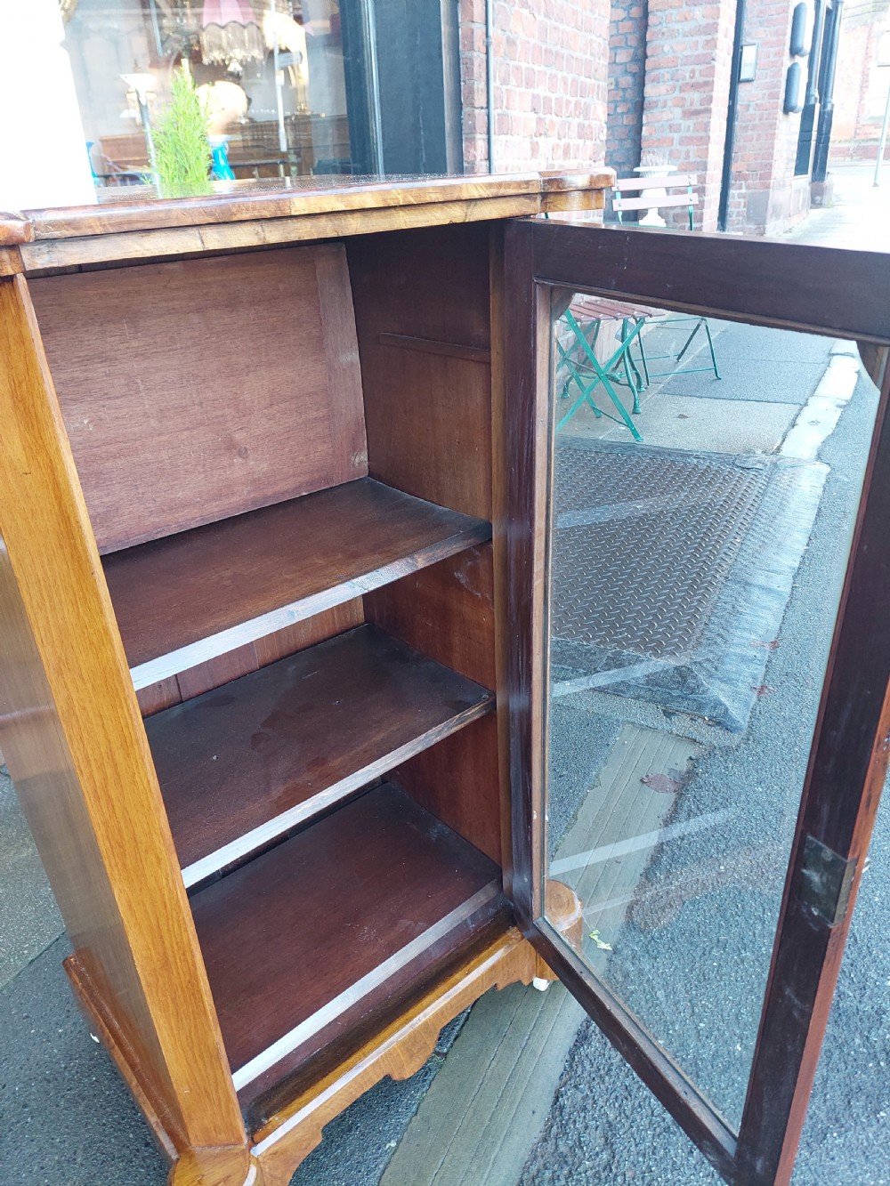A Victorian walnut music cabinet with a glazed single door, floral marquetry inlay, three internal shelves, and a plinth base on castors. View V