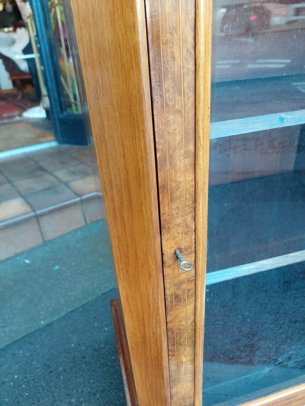 A Victorian walnut music cabinet with a glazed single door, floral marquetry inlay, three internal shelves, and a plinth base on castors. View VI