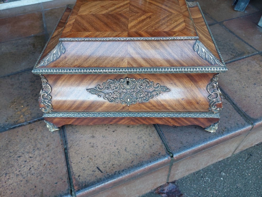 A Victorian kingwood jewellery box featuring a parquetry veneer pattern, serpentine sides, and silver-coloured ornamental corner mounts. View V
