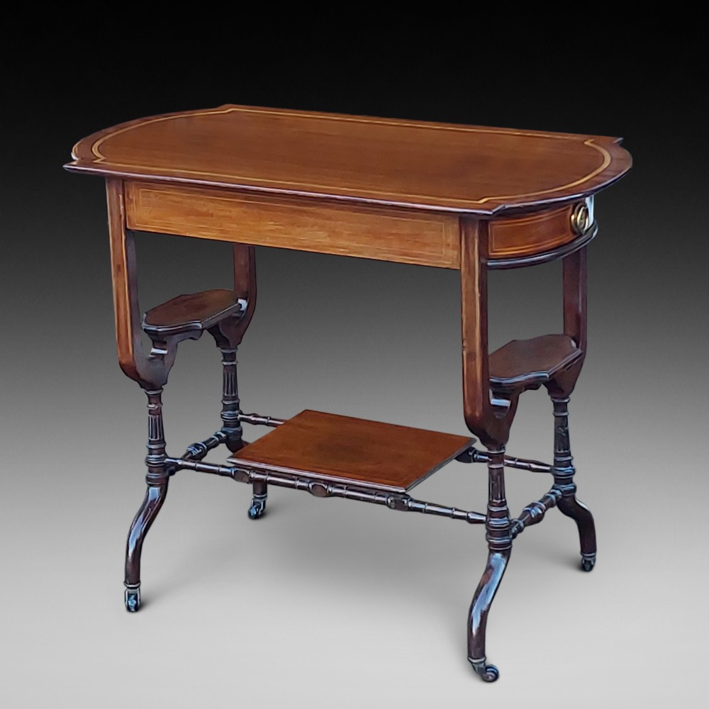 An Edwardian mahogany side table featuring decorative string inlay, a lower shelf, shaped side supports, and legs with brass castors.
