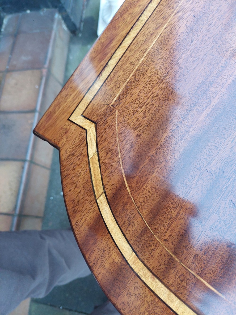 An Edwardian mahogany side table featuring decorative string inlay, a lower shelf, shaped side supports, and legs with brass castors. View III
