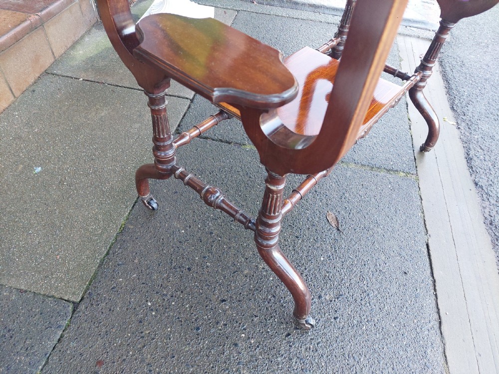 An Edwardian mahogany side table featuring decorative string inlay, a lower shelf, shaped side supports, and legs with brass castors. View V
