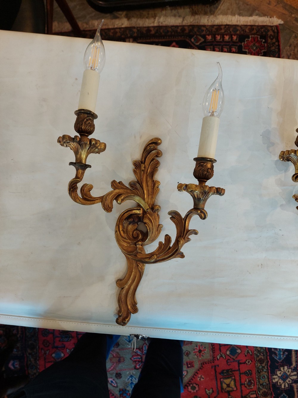 Set of four early twentieth-century cast brass two-arm wall lights featuring ornate Rococo scrolling foliage backplates and candle sockets. View II