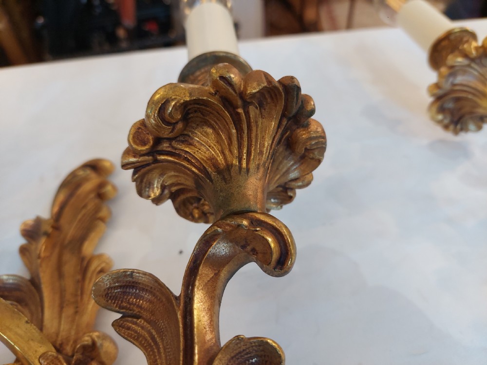 Set of four early twentieth-century cast brass two-arm wall lights featuring ornate Rococo scrolling foliage backplates and candle sockets. View VII