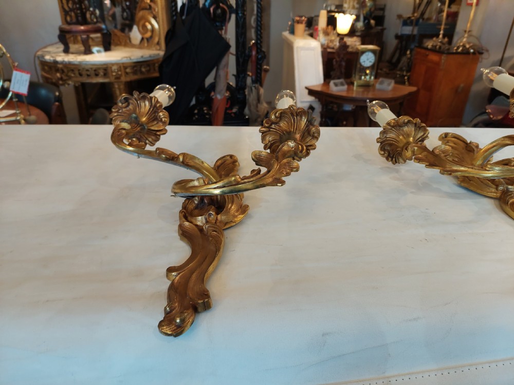 Set of four early twentieth-century cast brass two-arm wall lights featuring ornate Rococo scrolling foliage backplates and candle sockets. View VIII