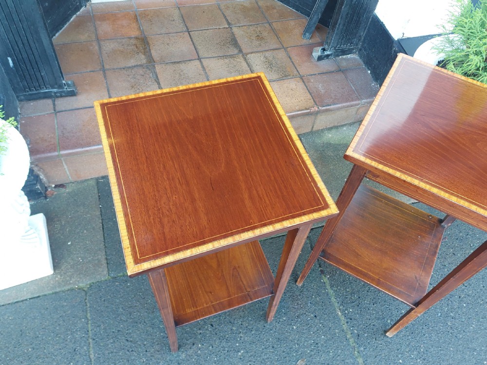 A pair of tall, slim Edwardian mahogany side tables featuring square tops with light wood inlaid borders, square tapered legs, and lower shelf tiers. View IV