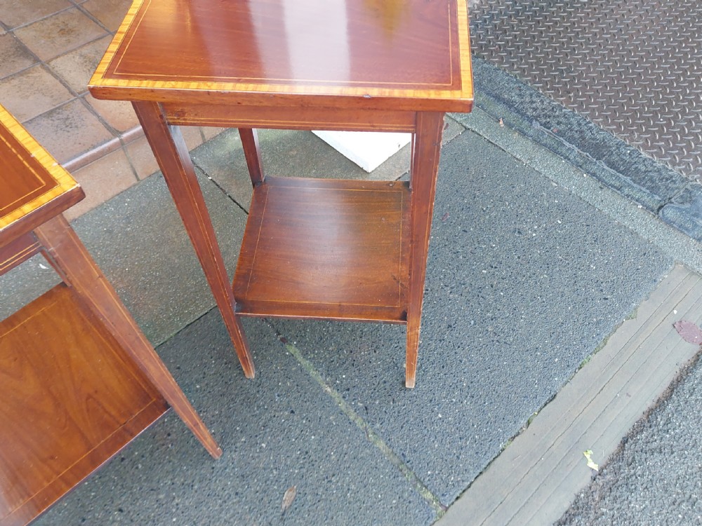 A pair of tall, slim Edwardian mahogany side tables featuring square tops with light wood inlaid borders, square tapered legs, and lower shelf tiers. View V