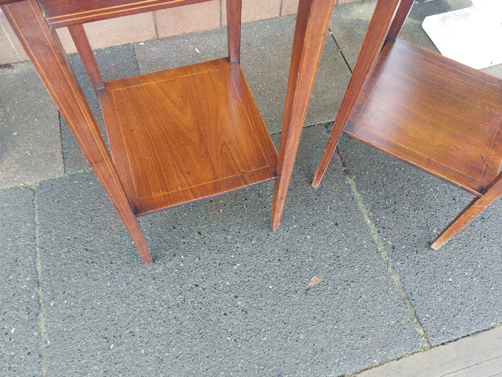 A pair of tall, slim Edwardian mahogany side tables featuring square tops with light wood inlaid borders, square tapered legs, and lower shelf tiers. View VI