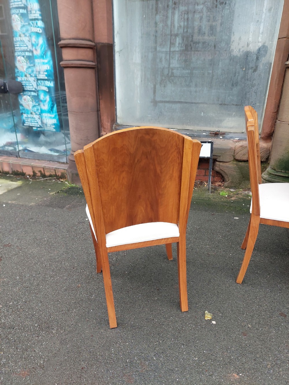 An Art Deco walnut dining suite comprising an oval pedestal table and six matching chairs with arched burr walnut backs and cream upholstered seats. View IV