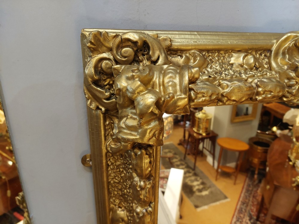 A rectangular 19th-century giltwood wall mirror featuring an ornate carved frame with sand-moulded gesso texture and scrolling foliage details. View III