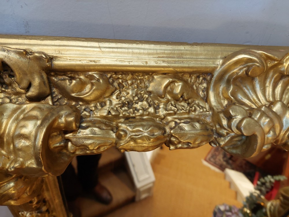 A rectangular 19th-century giltwood wall mirror featuring an ornate carved frame with sand-moulded gesso texture and scrolling foliage details. View V