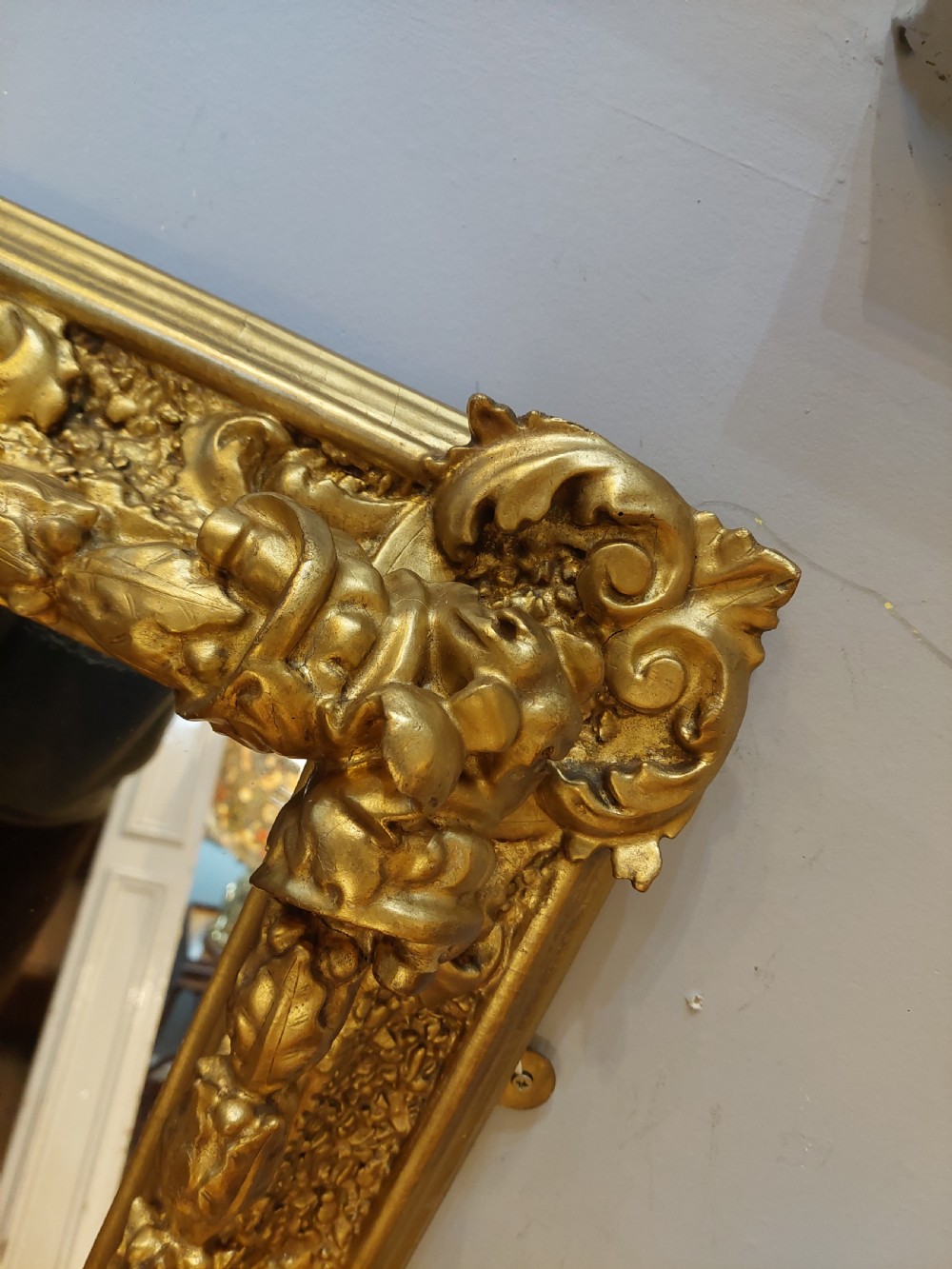 A rectangular 19th-century giltwood wall mirror featuring an ornate carved frame with sand-moulded gesso texture and scrolling foliage details. View VII