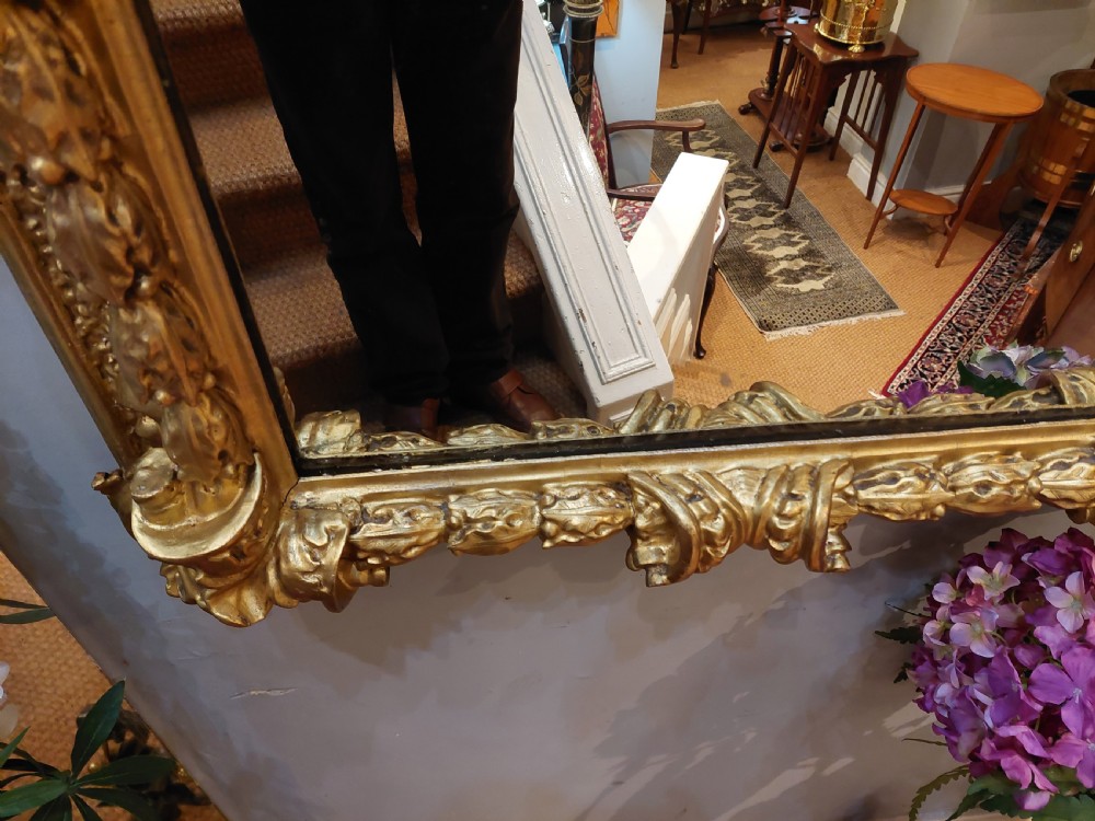 A rectangular 19th-century giltwood wall mirror featuring an ornate carved frame with sand-moulded gesso texture and scrolling foliage details. View IX
