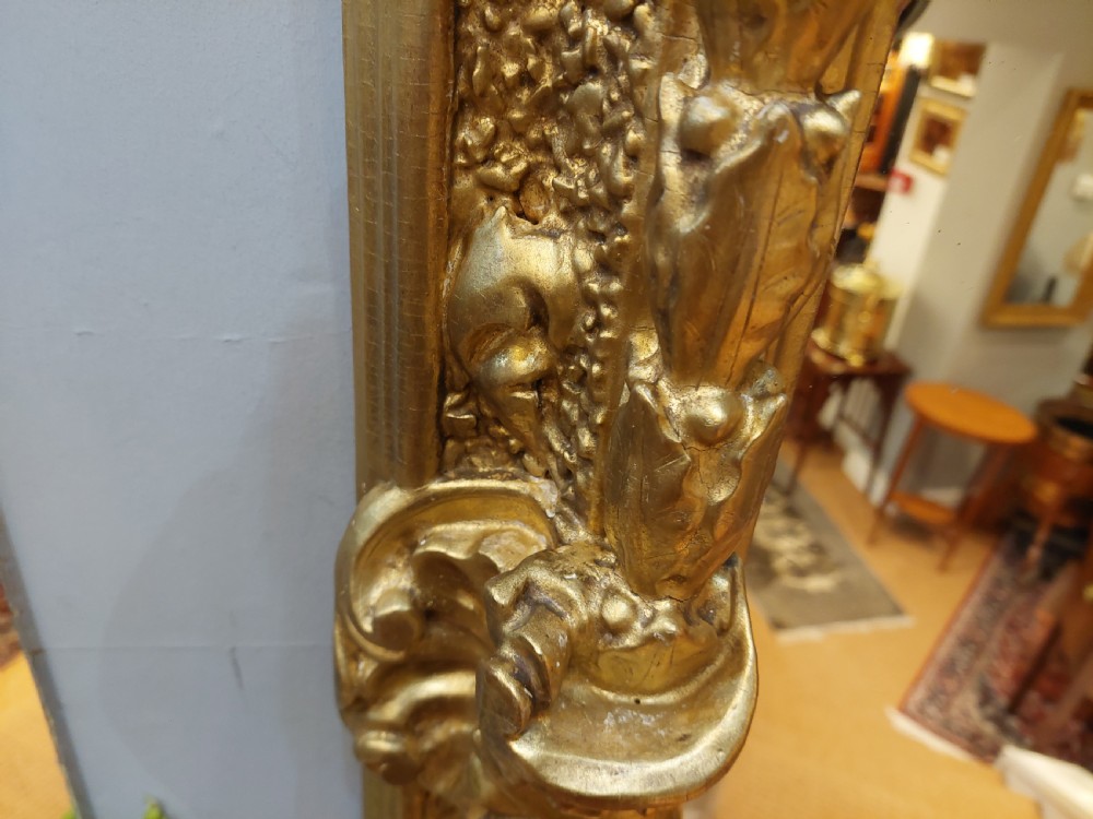 A rectangular 19th-century giltwood wall mirror featuring an ornate carved frame with sand-moulded gesso texture and scrolling foliage details. View X