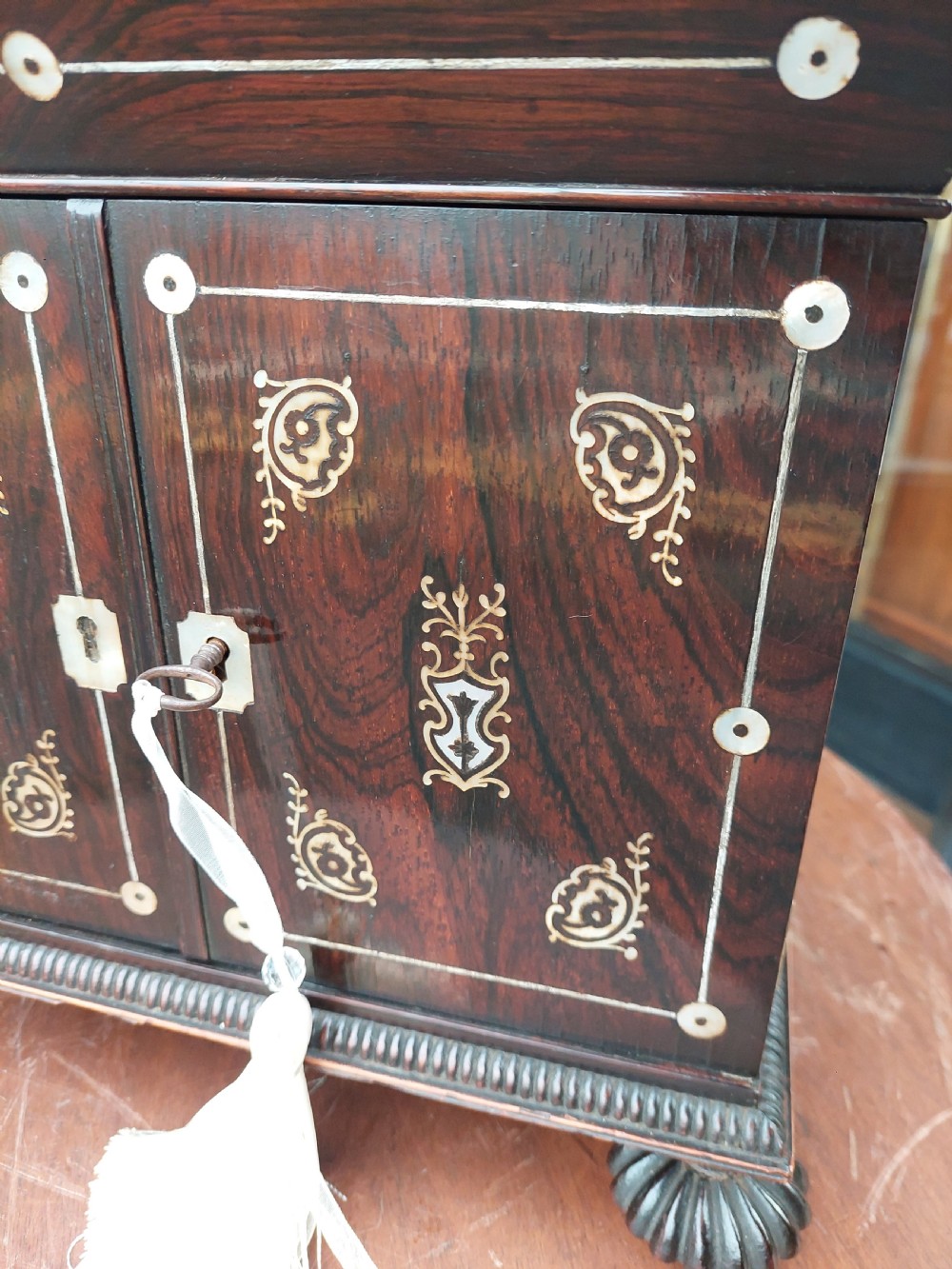 A nineteenth-century dark rosewood jewellery cabinet featuring mother-of-pearl decorative inlay, two front doors, a stepped lid, and turned feet. View V