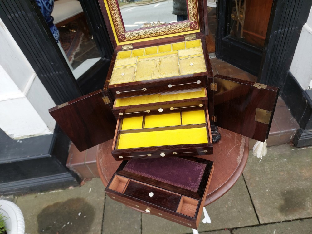 A nineteenth-century dark rosewood jewellery cabinet featuring mother-of-pearl decorative inlay, two front doors, a stepped lid, and turned feet. View VI