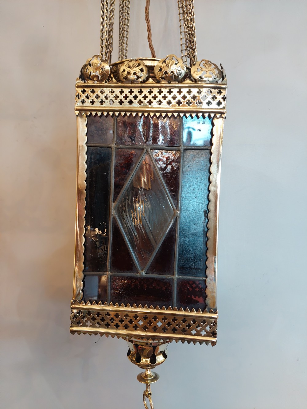 A Victorian hanging brass lantern with rectangular leaded glass panels displaying diamond motifs and suspended by delicate chains. View IV
