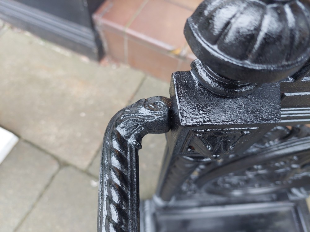 A black painted cast iron stick stand featuring elaborate foliate scrollwork, twisted rope columns, and a removable drip tray base. View V