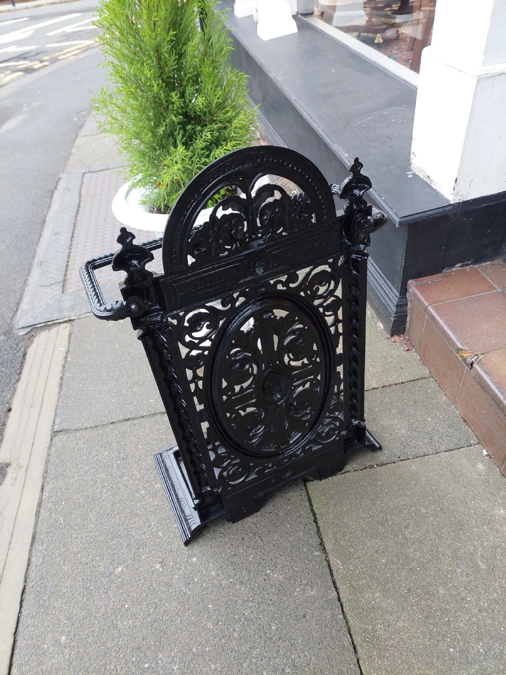 A black painted cast iron stick stand featuring elaborate foliate scrollwork, twisted rope columns, and a removable drip tray base. View VII