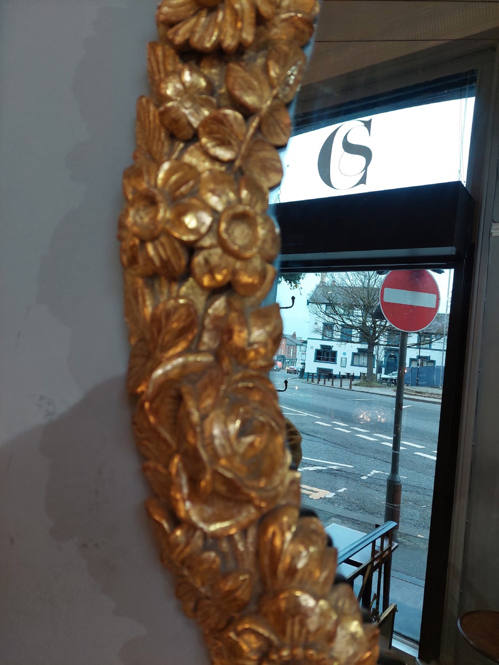 An oval Victorian wall mirror featuring a giltwood frame carved with floral motifs and a tied ribbon detail at the base. View IV