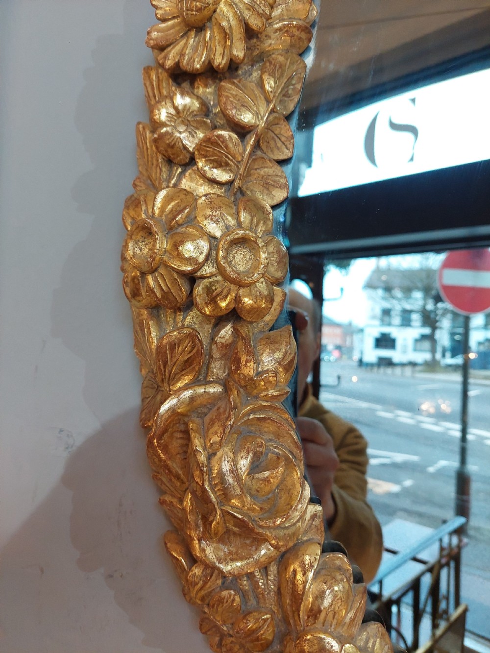 An oval Victorian wall mirror featuring a giltwood frame carved with floral motifs and a tied ribbon detail at the base. View VI