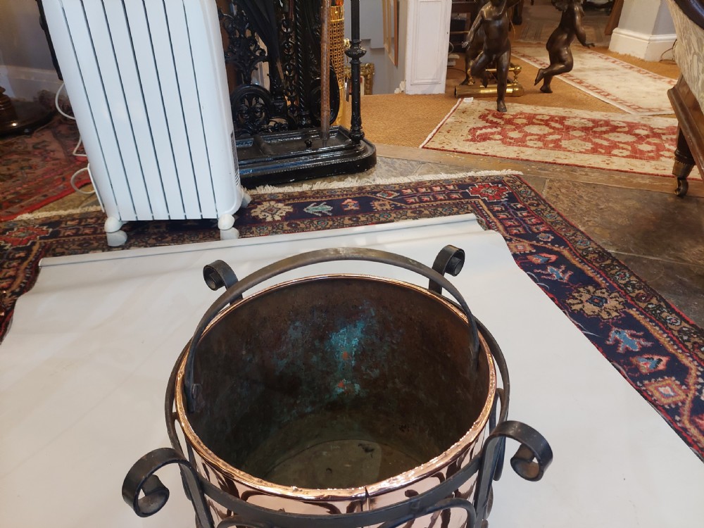 A cylindrical copper bucket set within a black wrought iron frame featuring scroll motifs and a curved carrying handle. View VI